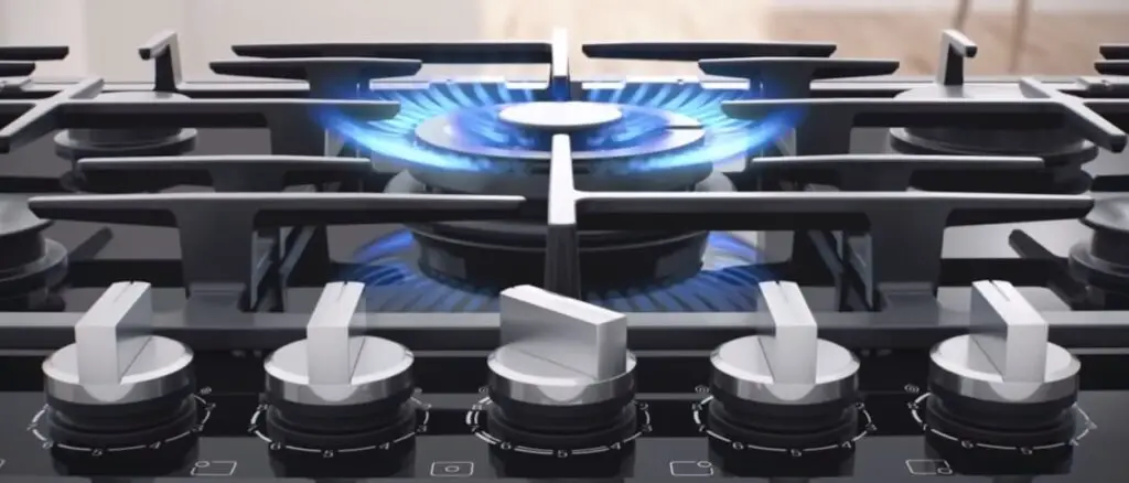 blue flames on a gas stove with different knobs and grates