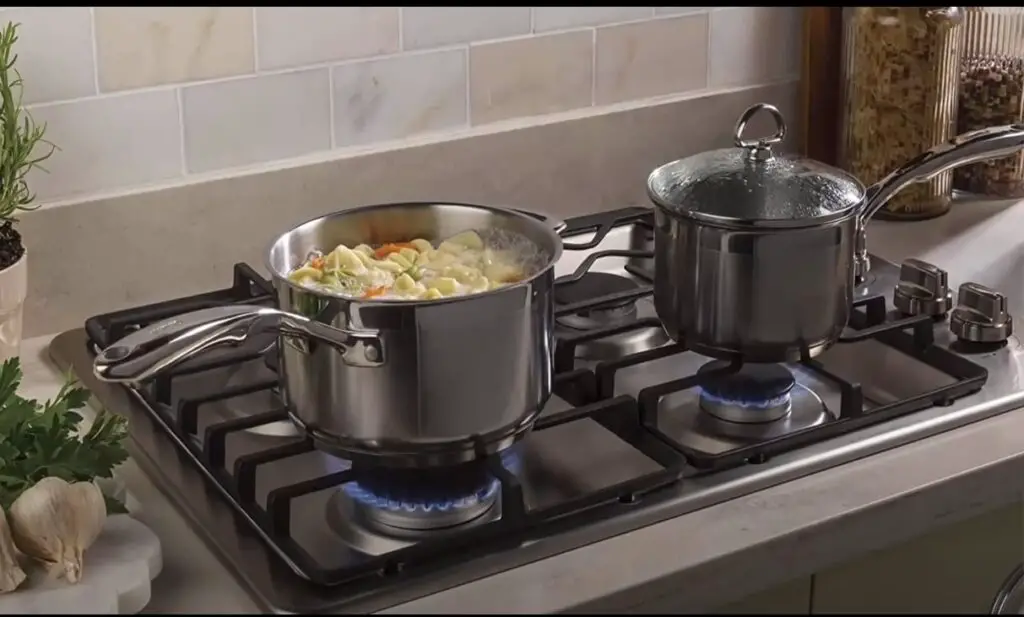 a picture of cookware on a lit gas stove. food is being cooked in the pan